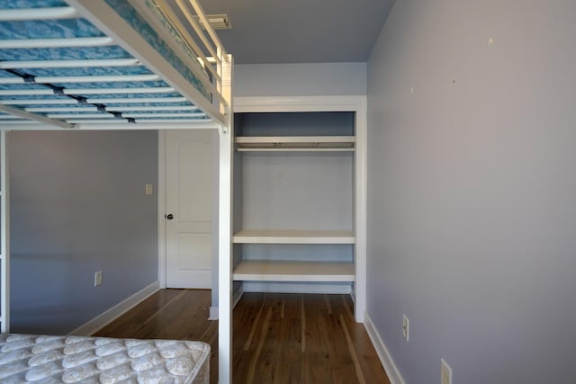 unfurnished bedroom with wood finished floors, a closet, and baseboards