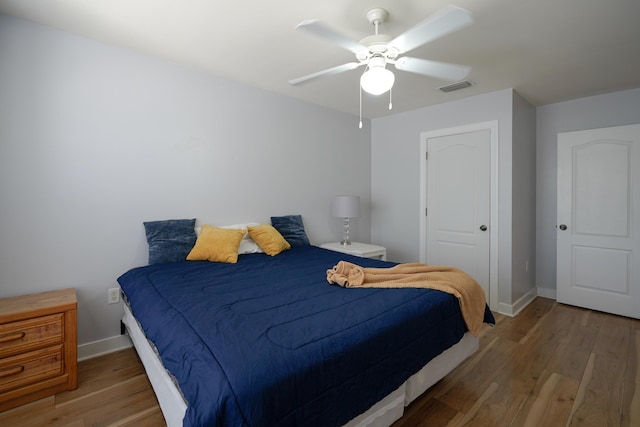 bedroom with a ceiling fan, wood finished floors, visible vents, and baseboards