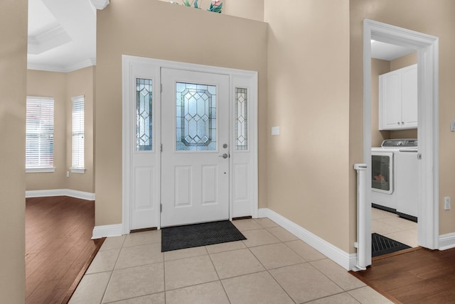 entrance foyer with crown molding, light wood-style floors, washing machine and clothes dryer, and baseboards