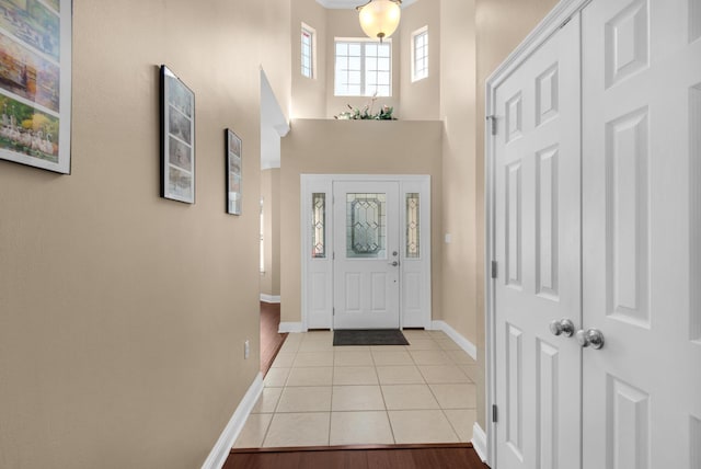 foyer entrance featuring a towering ceiling, baseboards, and light tile patterned flooring