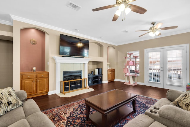 living room with visible vents, dark wood finished floors, baseboards, a tile fireplace, and ornamental molding