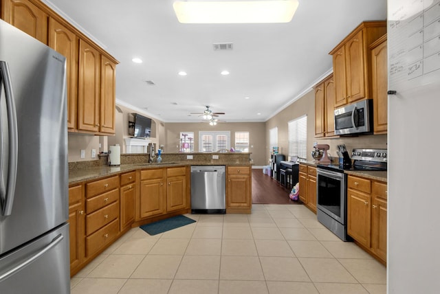 kitchen with a peninsula, light tile patterned floors, appliances with stainless steel finishes, and crown molding