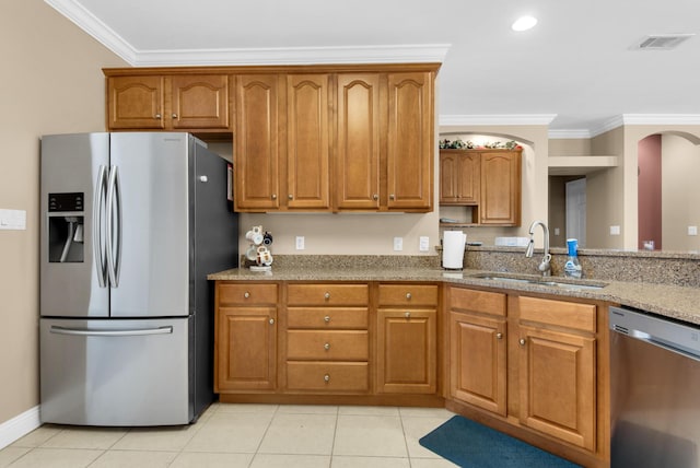 kitchen with visible vents, appliances with stainless steel finishes, brown cabinets, crown molding, and a sink