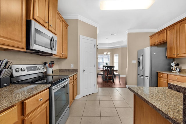 kitchen featuring stone countertops, appliances with stainless steel finishes, brown cabinetry, and ornamental molding