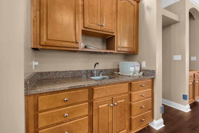 kitchen with baseboards, brown cabinetry, dark wood-style floors, open shelves, and a sink