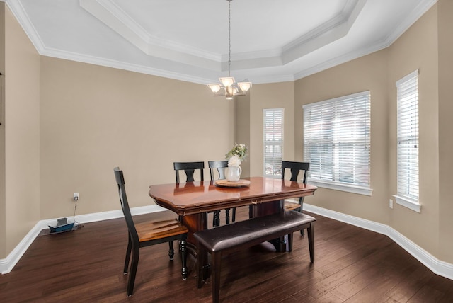 dining space featuring baseboards, a raised ceiling, dark wood-style floors, crown molding, and a notable chandelier