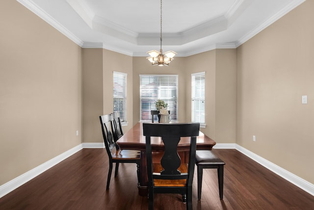 dining room featuring dark wood-type flooring, a tray ceiling, a chandelier, and baseboards