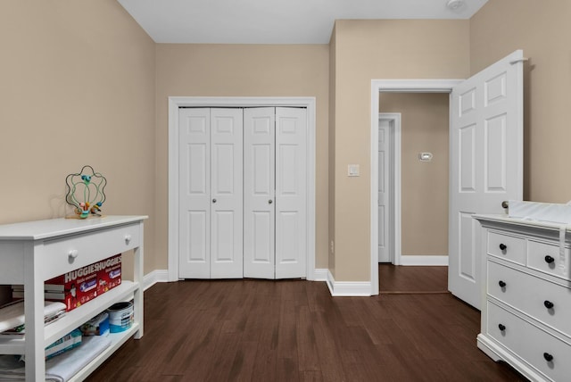 bedroom featuring dark wood-style flooring, a closet, and baseboards