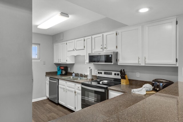 kitchen with dark wood-type flooring, stainless steel appliances, sink, and white cabinets