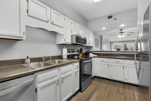 kitchen featuring appliances with stainless steel finishes, dark hardwood / wood-style flooring, sink, and white cabinets