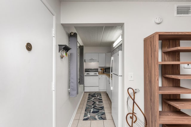 corridor featuring light tile patterned floors and a textured ceiling