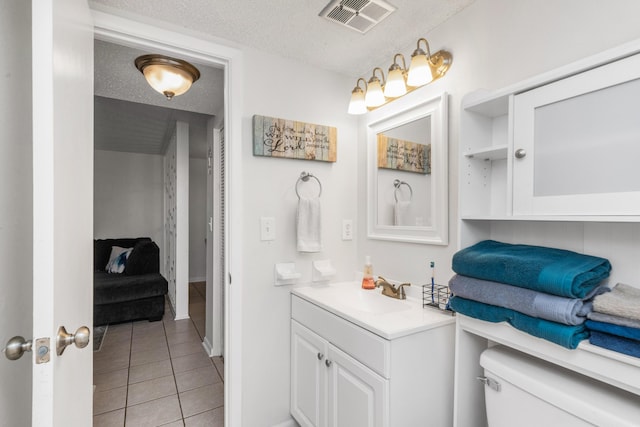 bathroom with tile patterned floors, a textured ceiling, toilet, and vanity