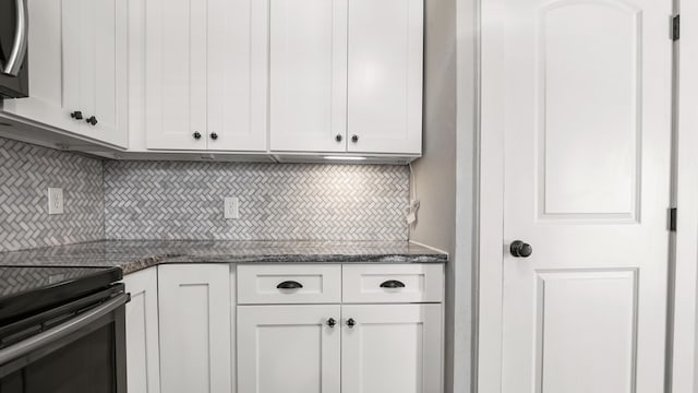 kitchen featuring tasteful backsplash, dark stone countertops, stainless steel electric stove, and white cabinets