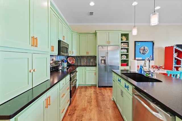 kitchen with decorative light fixtures, stainless steel appliances, green cabinetry, and sink