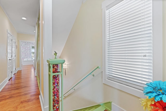 hallway with ornamental molding and light hardwood / wood-style floors