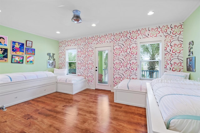 bedroom featuring hardwood / wood-style flooring, crown molding, and access to exterior