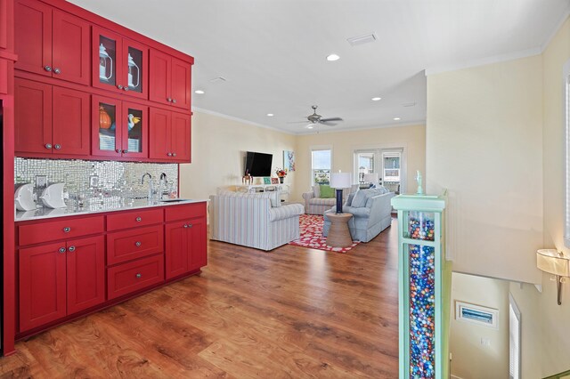 kitchen featuring sink, backsplash, dark wood-type flooring, and crown molding