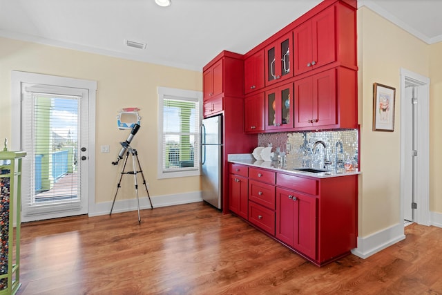kitchen featuring crown molding, stainless steel fridge, backsplash, dark hardwood / wood-style flooring, and sink