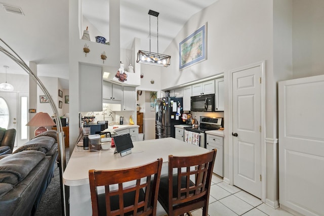 dining area featuring a chandelier, visible vents, a high ceiling, and light tile patterned flooring