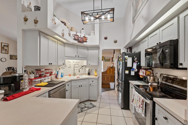 kitchen with a sink, black appliances, hanging light fixtures, and light countertops