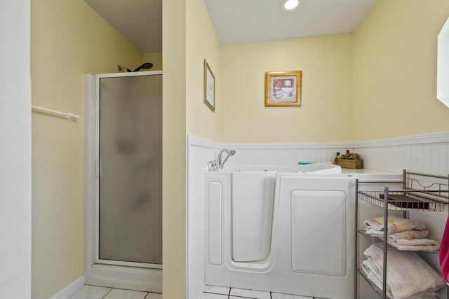 bathroom featuring a wainscoted wall and a shower stall