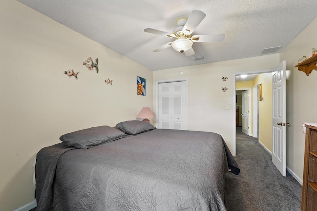 bedroom featuring dark colored carpet, visible vents, ceiling fan, and a textured ceiling