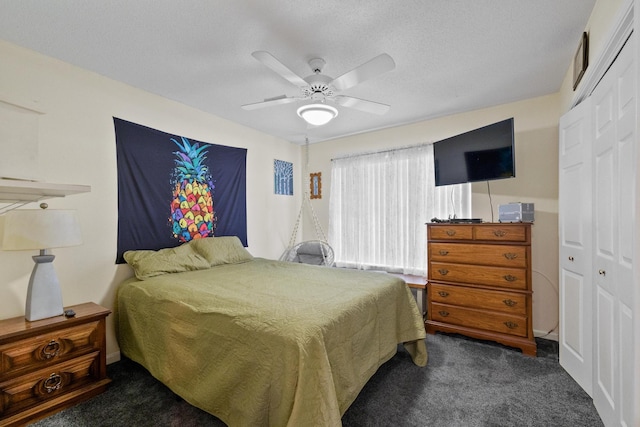 bedroom featuring ceiling fan, a textured ceiling, dark carpet, and a closet