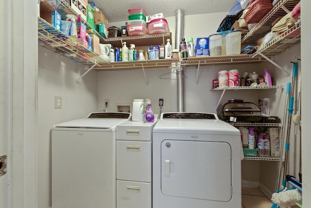 clothes washing area featuring washer and dryer, laundry area, tile patterned flooring, and a textured ceiling