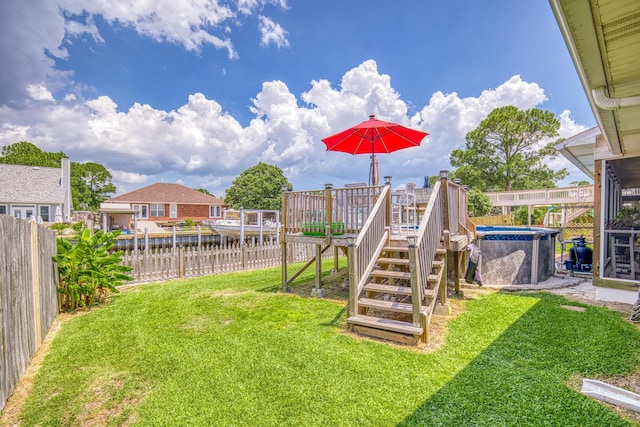 view of yard featuring a fenced in pool, a fenced backyard, a deck with water view, and stairs