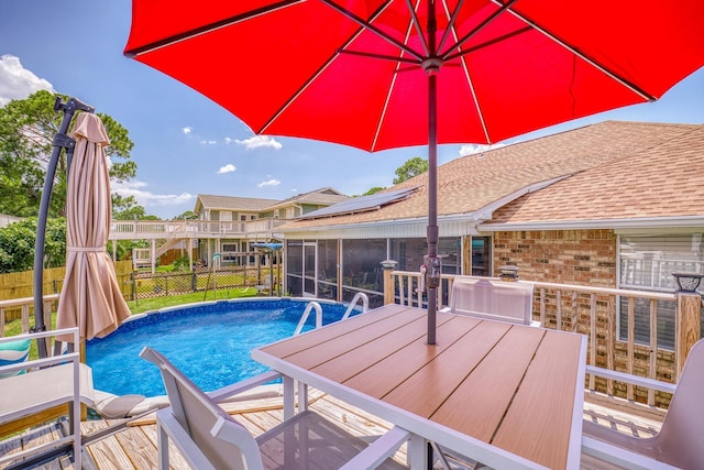 outdoor pool with outdoor dining space, fence, and a sunroom