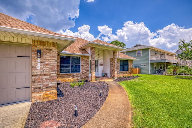 view of front of home featuring a garage, roof with shingles, a front yard, and brick siding