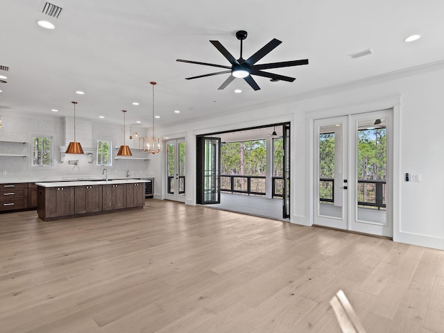 unfurnished living room with ceiling fan with notable chandelier and light wood-type flooring