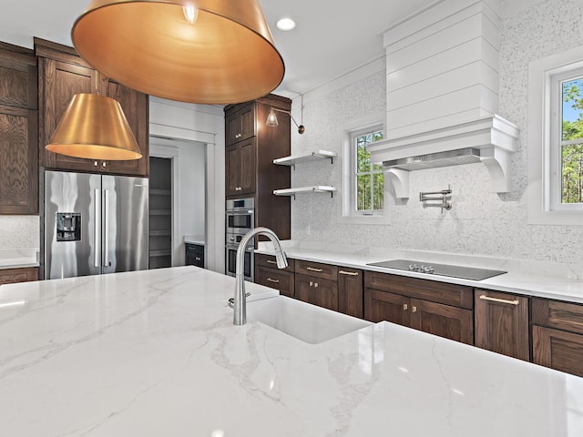 kitchen with sink, a wealth of natural light, stainless steel appliances, and light stone countertops