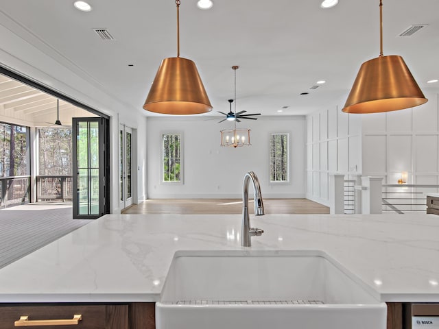 kitchen with sink, decorative light fixtures, light stone countertops, and ceiling fan