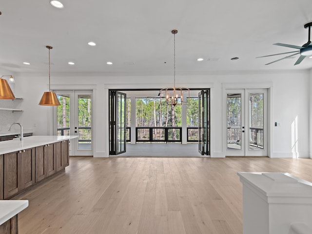 kitchen with ceiling fan with notable chandelier, decorative light fixtures, sink, light wood-type flooring, and french doors