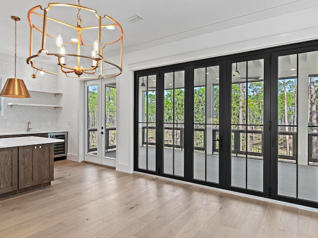 interior space with wine cooler, sink, light hardwood / wood-style floors, and a chandelier