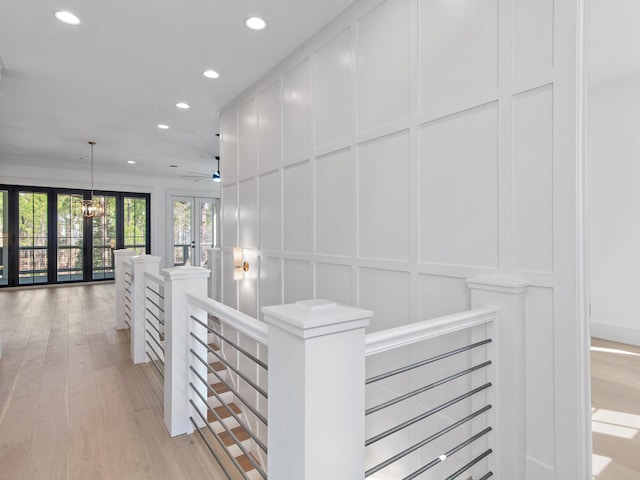 corridor with an inviting chandelier, light hardwood / wood-style floors, and french doors