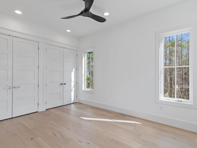 unfurnished bedroom featuring two closets, ceiling fan, and light wood-type flooring