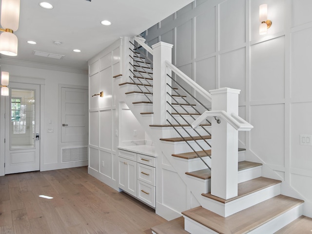 entryway with ornamental molding and light wood-type flooring