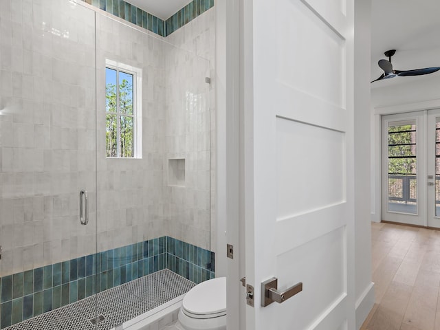 bathroom with a shower with shower door, wood-type flooring, ceiling fan, toilet, and french doors