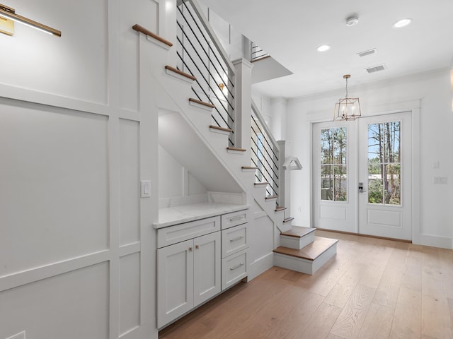 entryway featuring light hardwood / wood-style floors, french doors, and a chandelier