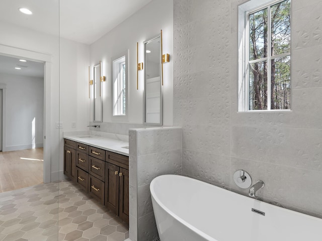 bathroom featuring tile walls, vanity, and a bathing tub