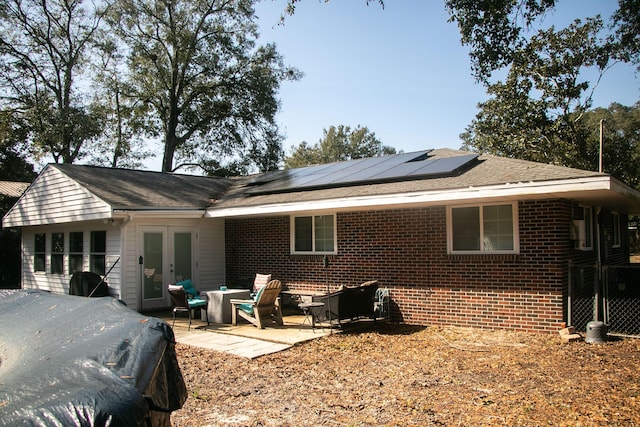 rear view of property with french doors, a patio area, and solar panels