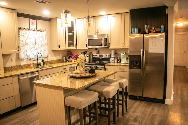 kitchen with sink, a breakfast bar area, appliances with stainless steel finishes, dark hardwood / wood-style floors, and a kitchen island