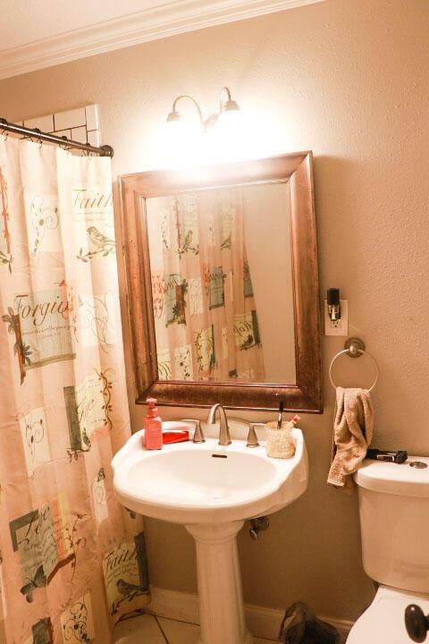 bathroom with ornamental molding, sink, and toilet