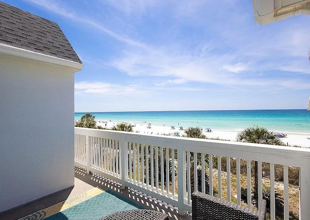 balcony with a water view and a view of the beach