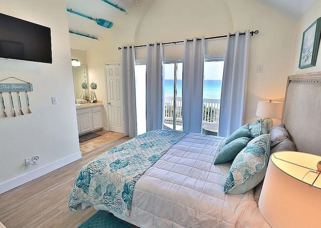 bedroom featuring a water view, lofted ceiling, access to exterior, and light hardwood / wood-style floors