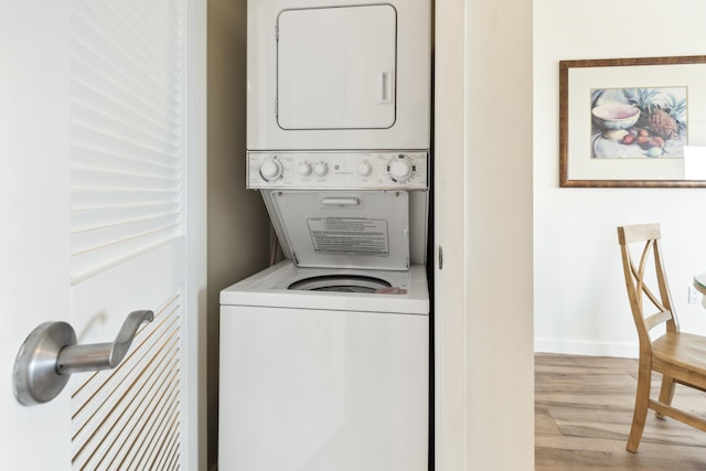 clothes washing area with stacked washer / drying machine and light wood-type flooring