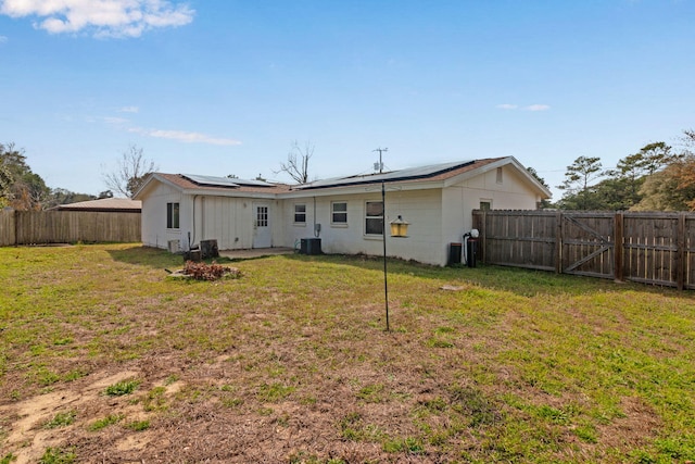 back of house with a yard, a fenced backyard, a gate, and roof mounted solar panels