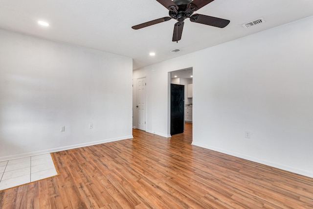 unfurnished room featuring light wood-style floors, baseboards, visible vents, and ceiling fan